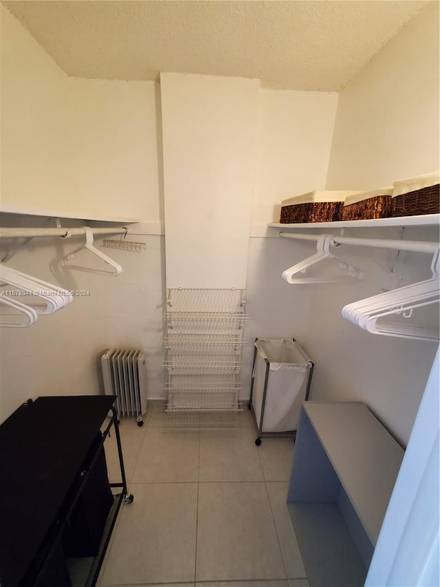 spacious closet with radiator heating unit and light tile patterned flooring