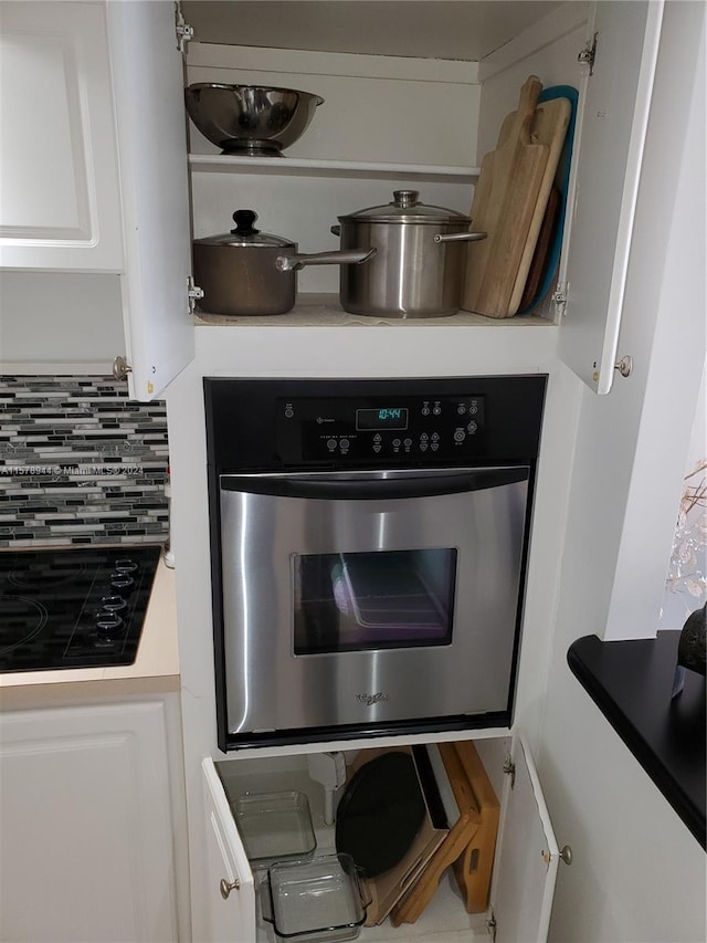 kitchen featuring oven, black cooktop, white cabinetry, and tasteful backsplash