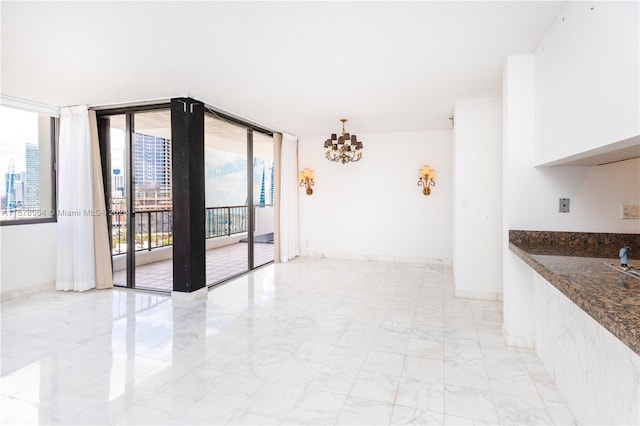 empty room featuring an inviting chandelier, a wall of windows, and light tile floors