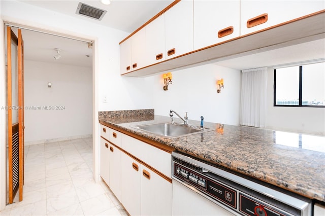 kitchen featuring white cabinetry, light tile floors, sink, dark stone counters, and dishwasher