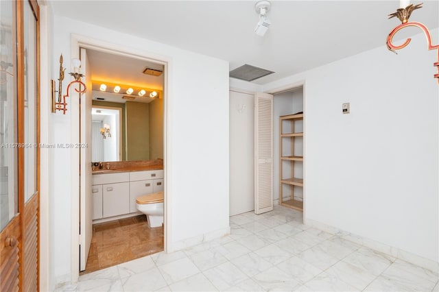 unfurnished bedroom featuring sink, ensuite bathroom, and light tile flooring