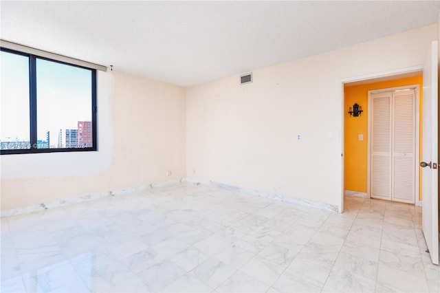 empty room featuring a textured ceiling and light tile flooring