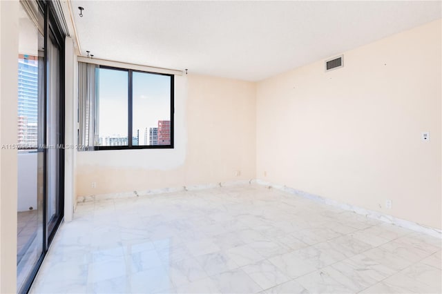 unfurnished room with a wall of windows and light tile floors