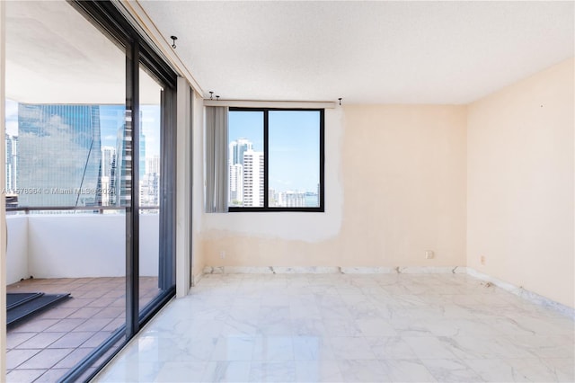 tiled spare room with floor to ceiling windows and a textured ceiling