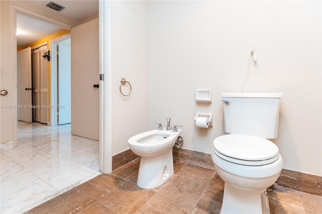 bathroom featuring toilet, a bidet, and tile flooring