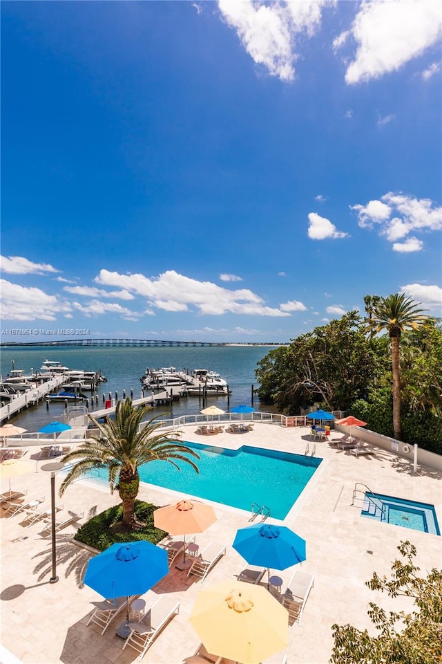 view of swimming pool featuring a dock, a patio, and a water view