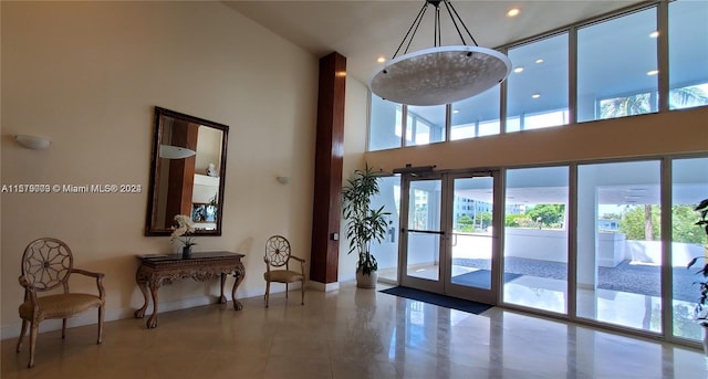 interior space featuring plenty of natural light, french doors, tile floors, and a high ceiling