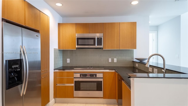 kitchen with tasteful backsplash, light tile patterned floors, dark stone countertops, kitchen peninsula, and stainless steel appliances