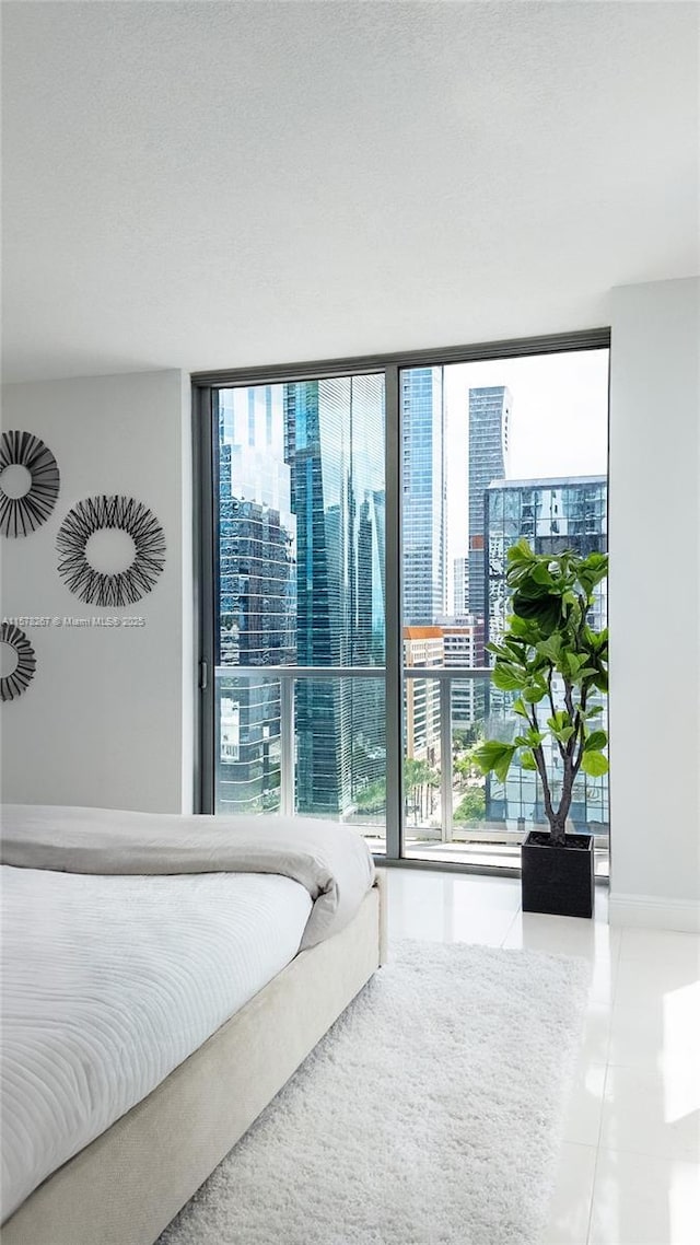 tiled bedroom featuring a wall of windows, access to exterior, and multiple windows