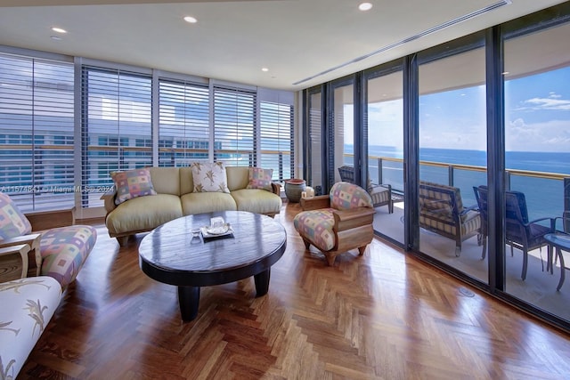 living room featuring a water view, parquet flooring, and a wall of windows