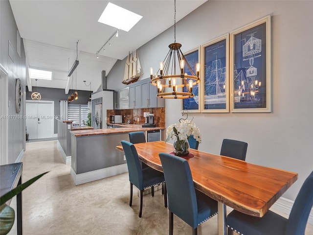 dining area featuring vaulted ceiling with skylight, sink, track lighting, and a chandelier