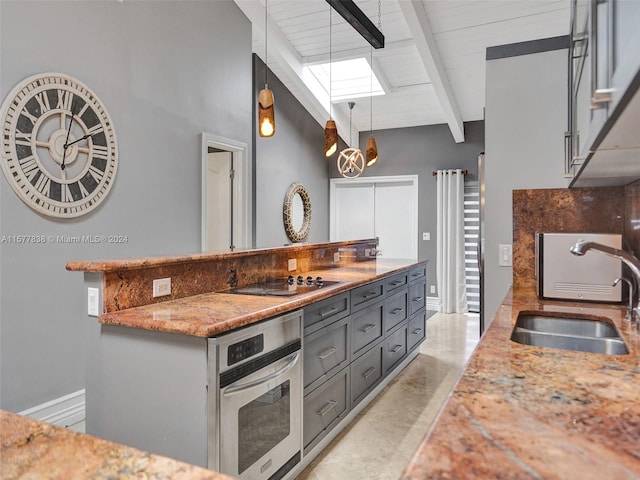 kitchen with decorative light fixtures, beam ceiling, a skylight, sink, and stainless steel oven