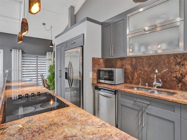 kitchen with light stone counters, appliances with stainless steel finishes, sink, tasteful backsplash, and vaulted ceiling