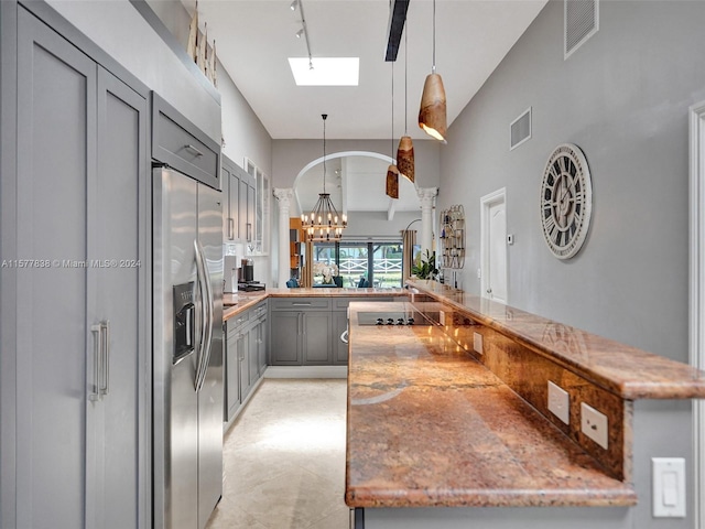 kitchen with hanging light fixtures, gray cabinetry, kitchen peninsula, a skylight, and high quality fridge