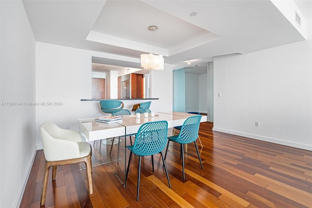 dining space with a tray ceiling and dark hardwood / wood-style floors