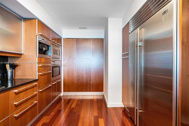 kitchen with dark hardwood / wood-style flooring and built in appliances