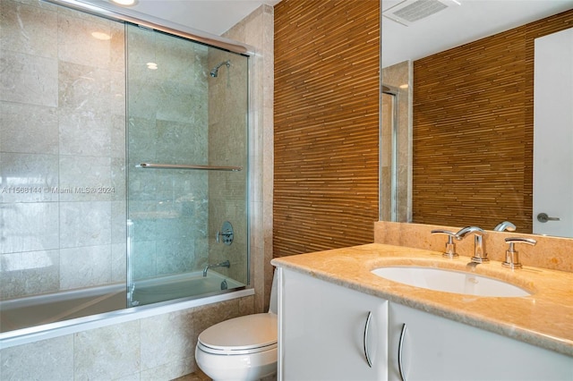 full bathroom featuring combined bath / shower with glass door, vanity, and toilet