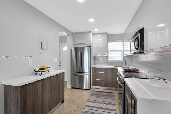 kitchen with sink, appliances with stainless steel finishes, backsplash, and light tile patterned floors