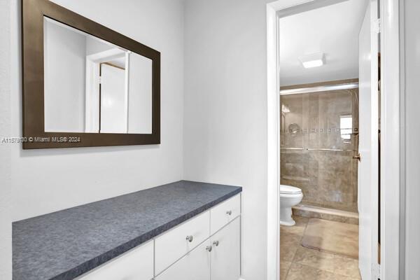 bathroom featuring vanity, toilet, a shower with door, and tile patterned floors