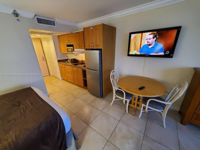 kitchen featuring ornamental molding, exhaust hood, sink, light tile patterned floors, and stainless steel refrigerator