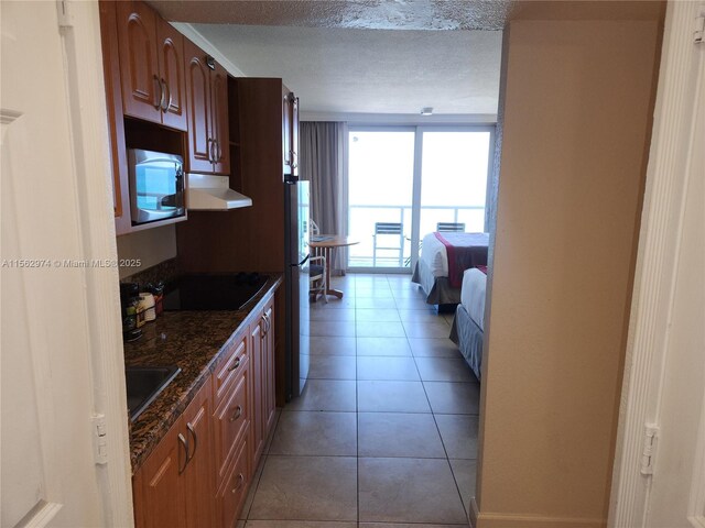 kitchen with sink, crown molding, dark stone countertops, light tile patterned floors, and stainless steel appliances