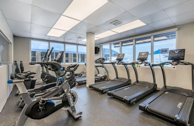 workout area with a paneled ceiling and a healthy amount of sunlight