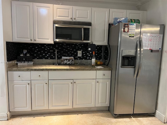 kitchen with white cabinets, light tile flooring, appliances with stainless steel finishes, and backsplash