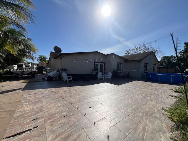 view of front of property with a fenced in pool, a patio area, and french doors