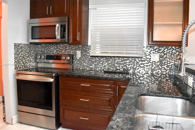 kitchen with backsplash, dark stone countertops, and appliances with stainless steel finishes