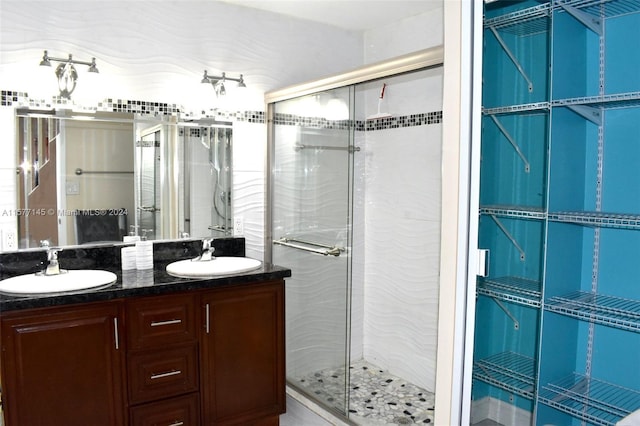 bathroom featuring a shower with shower door and double vanity