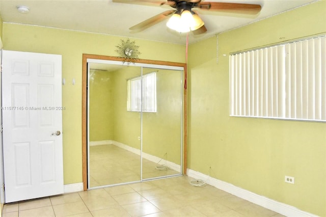 unfurnished bedroom with tile floors, ceiling fan, and a closet