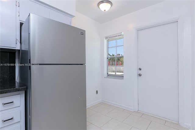 kitchen featuring white cabinets, light tile floors, and dark stone counters