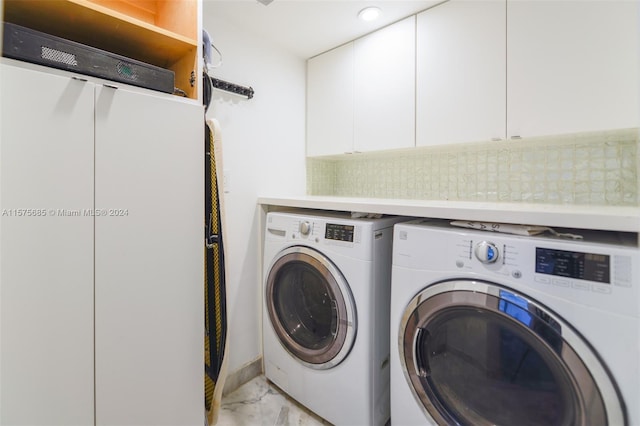 laundry area featuring washing machine and clothes dryer and cabinets