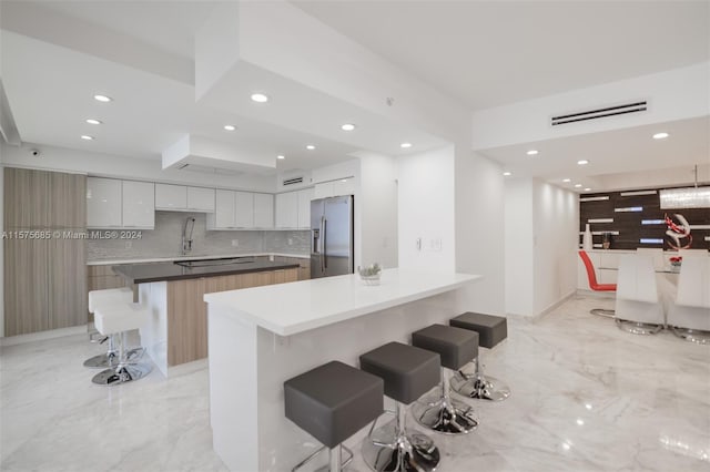 kitchen with backsplash, a kitchen bar, white cabinetry, a spacious island, and stainless steel fridge with ice dispenser