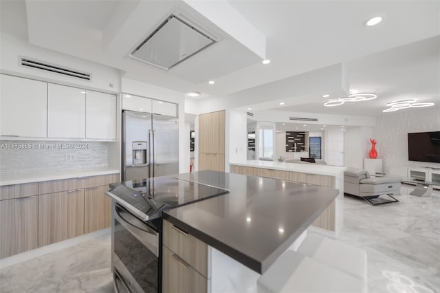 kitchen featuring white cabinets, backsplash, a kitchen island, and appliances with stainless steel finishes