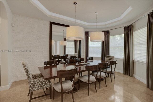 dining space with crown molding, a tray ceiling, and ornate columns