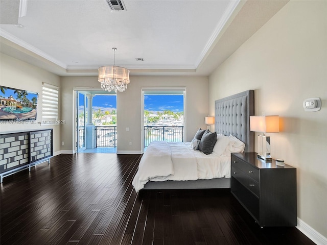 bedroom with a chandelier, ornamental molding, dark hardwood / wood-style floors, a tray ceiling, and access to exterior