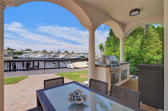 view of patio / terrace with grilling area, a water view, and exterior kitchen