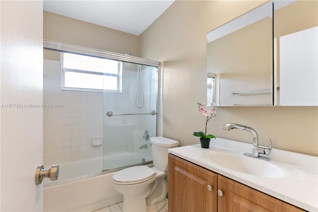 full bathroom featuring oversized vanity, tile floors, toilet, and bath / shower combo with glass door