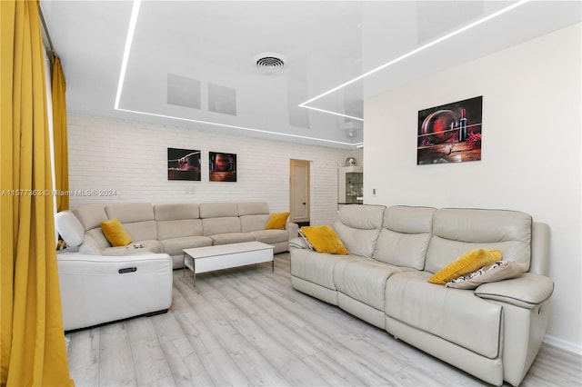 living room featuring brick wall and light wood-type flooring