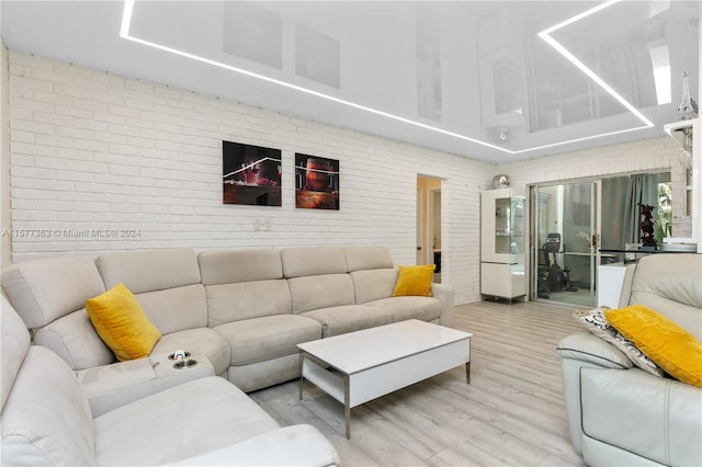 living room with brick wall and light wood-type flooring