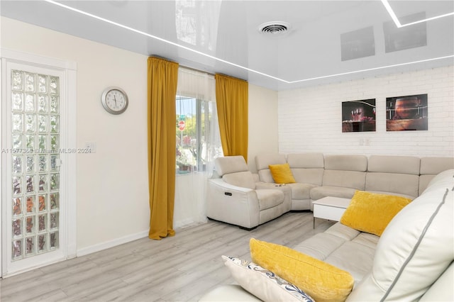 living room featuring brick wall and light wood-type flooring