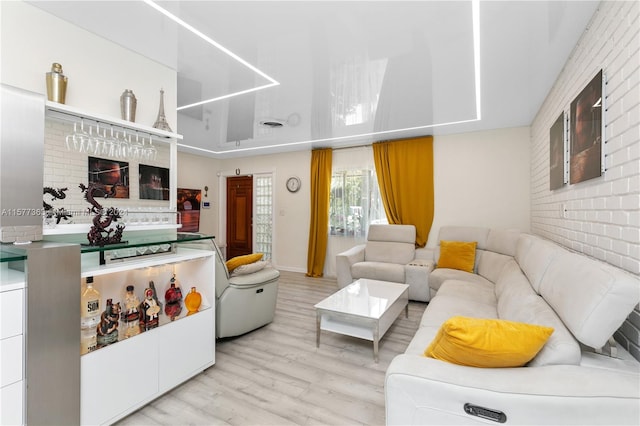 living room featuring brick wall and light hardwood / wood-style flooring