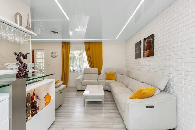 living room featuring brick wall and light hardwood / wood-style flooring