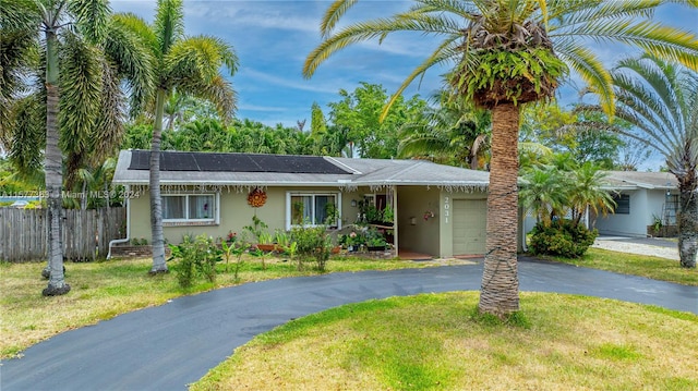 ranch-style house featuring solar panels, a garage, and a front yard