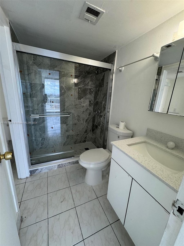 bathroom featuring a shower with door, vanity, tile floors, and toilet