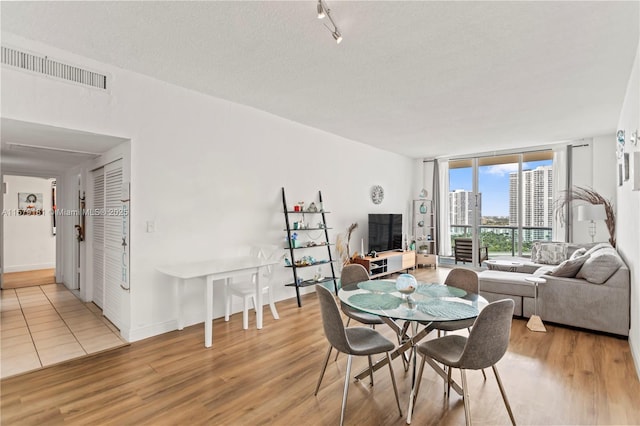 dining room featuring a wall of windows, a textured ceiling, and light hardwood / wood-style floors