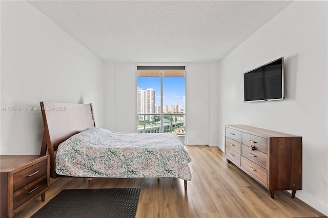 bedroom featuring a textured ceiling and light hardwood / wood-style flooring