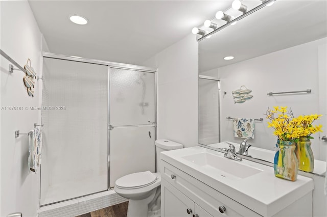 bathroom featuring toilet, walk in shower, hardwood / wood-style flooring, and vanity