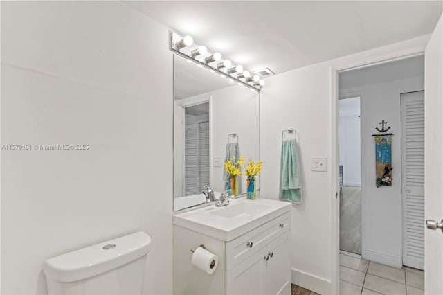 bathroom with toilet, vanity, and tile patterned flooring